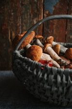 A rustic kitchen scene with a basket of assorted fresh organic mushrooms ready for cooking.
