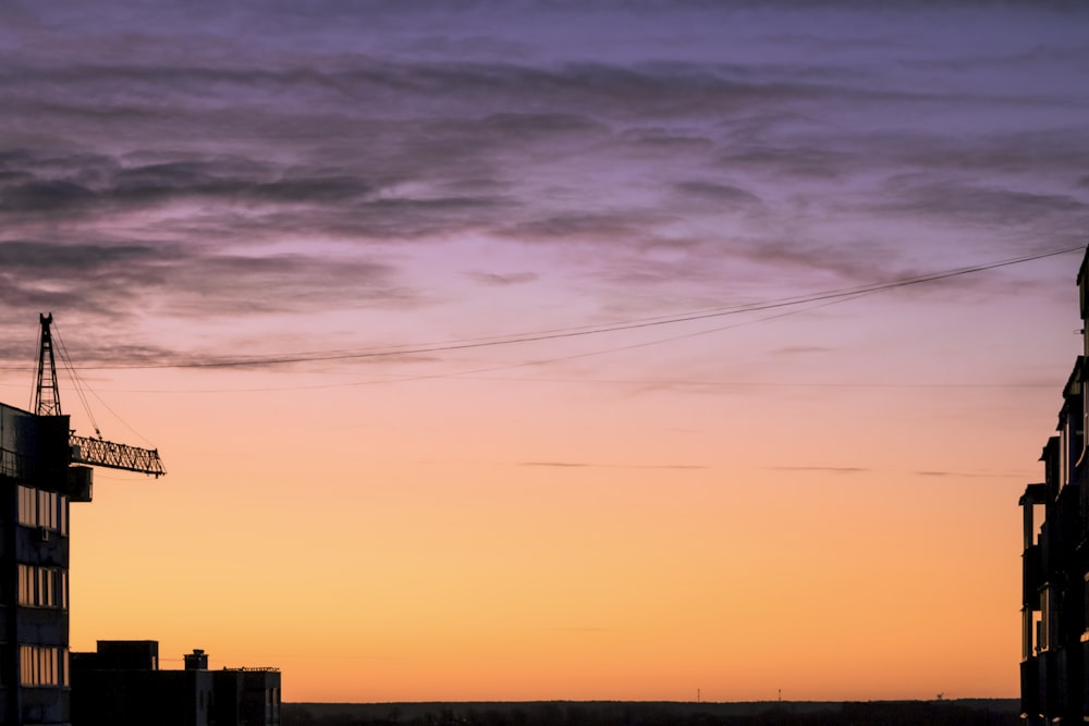 a sunset view of a building with a crane in the distance