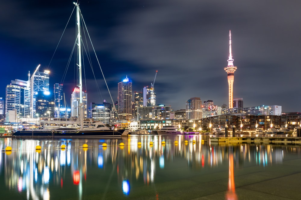 a city skyline at night with a sailboat in the foreground