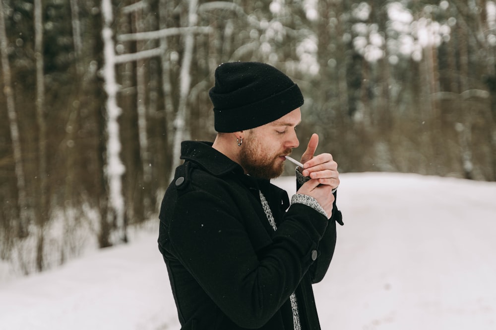 a man standing in the snow smoking a cigarette