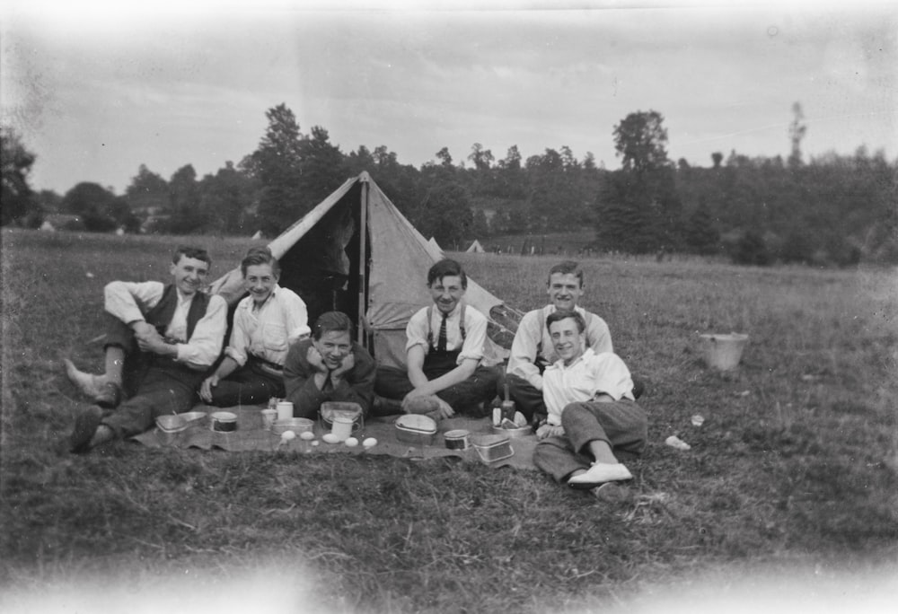 a group of people sitting around a tent in a field
