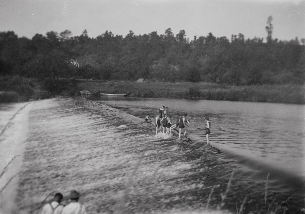 a group of people riding horses across a river