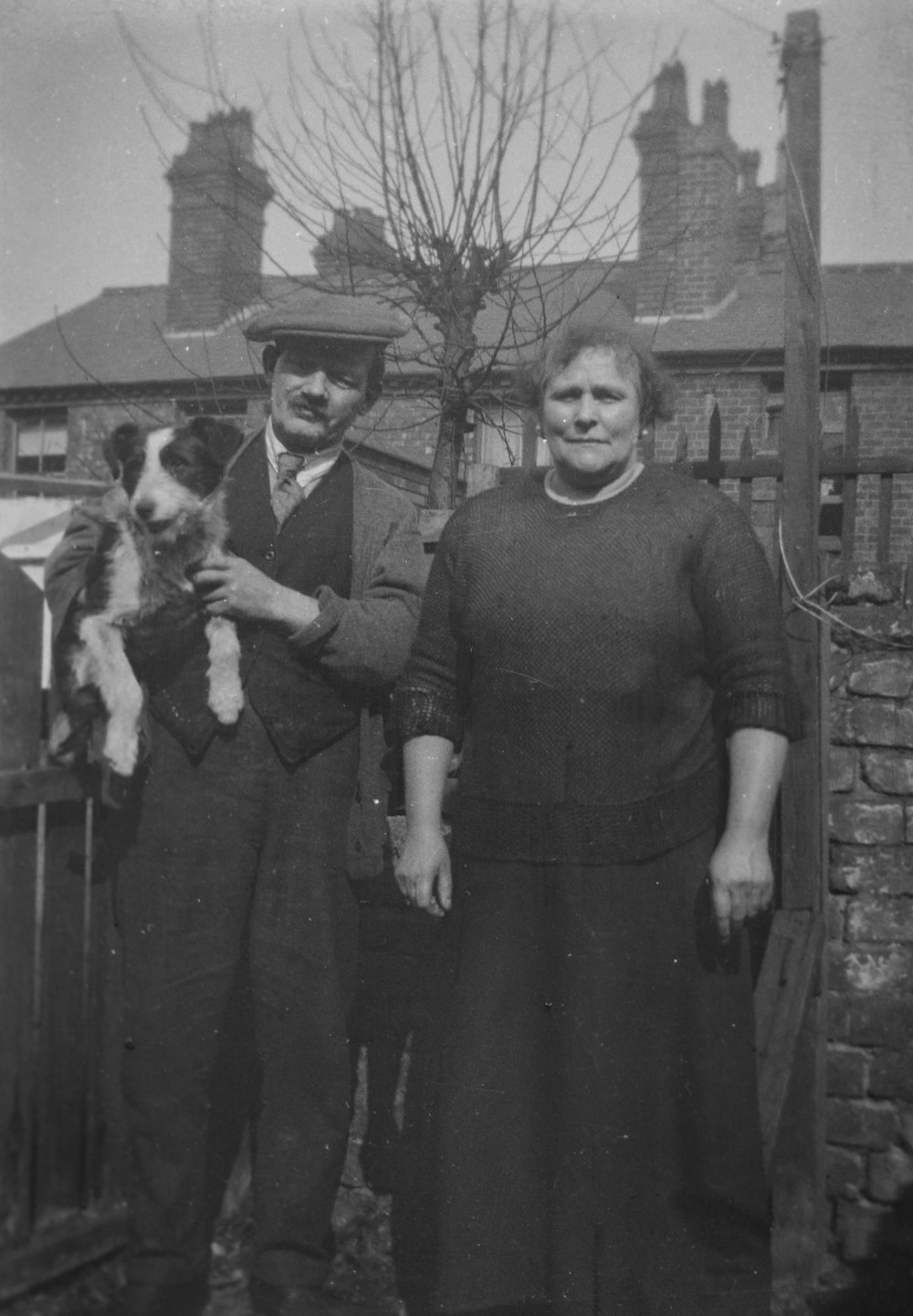 uma velha foto em preto e branco de um homem e uma mulher segurando um cachorro
