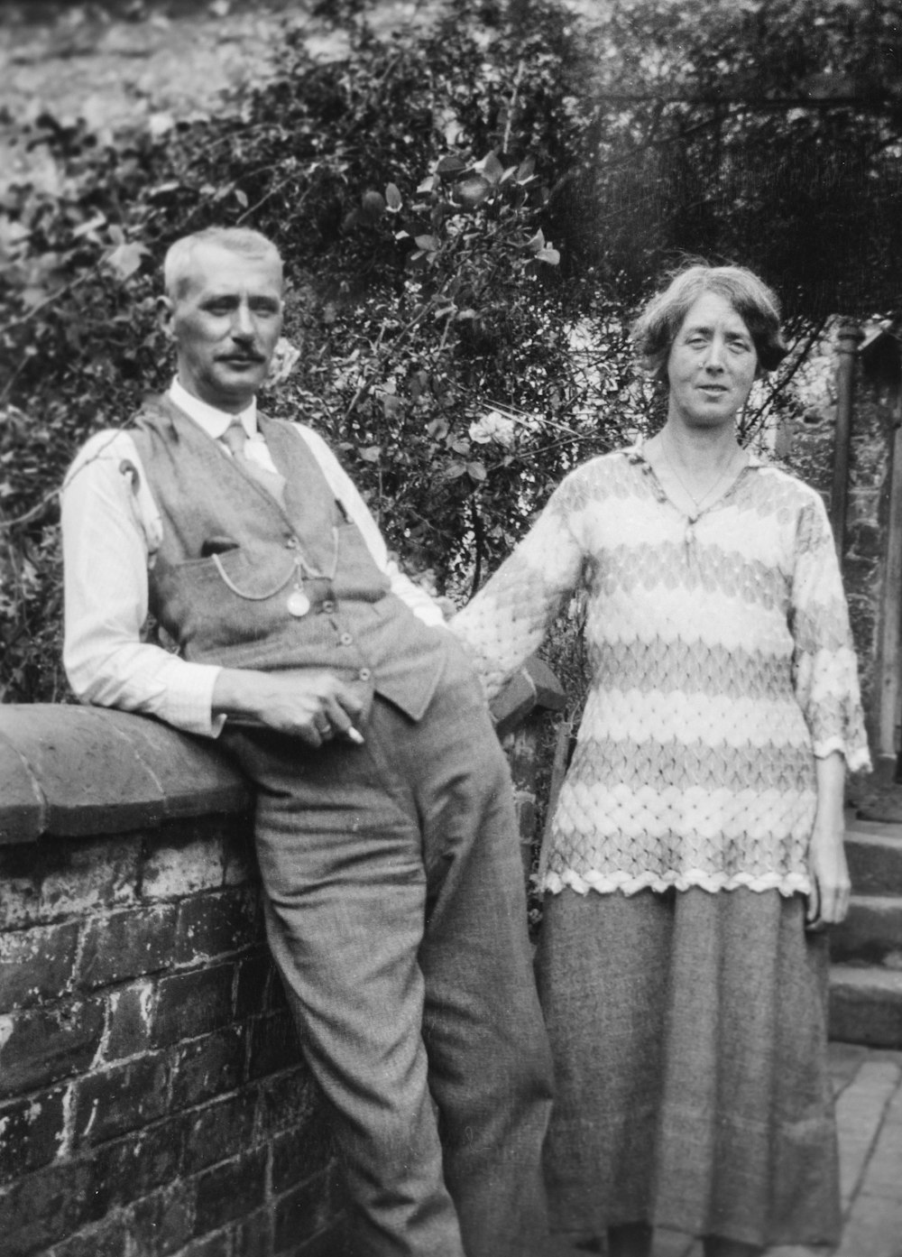 an old photo of a man and woman leaning against a wall