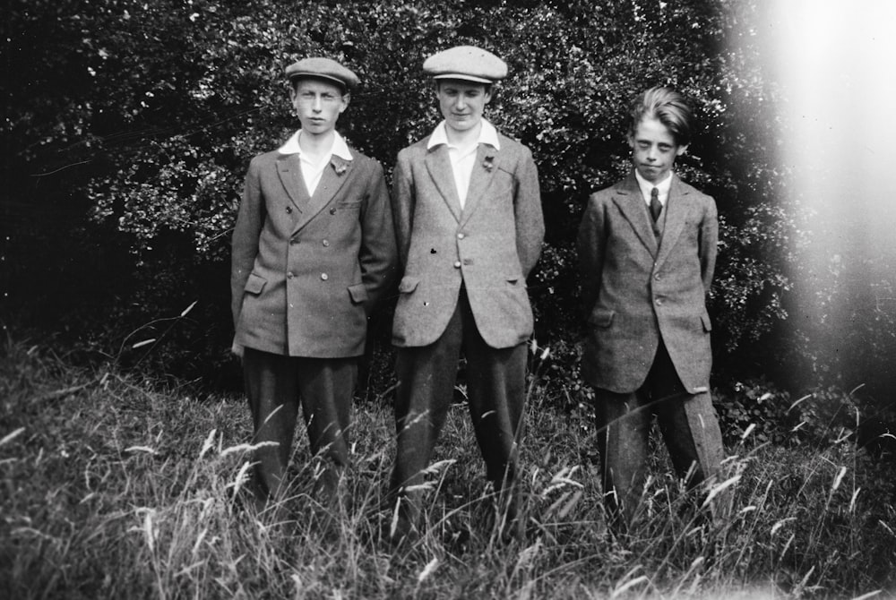 a black and white photo of three boys in suits