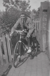 Murdered by Darkness Image a man riding a bike down a sidewalk next to a fence
