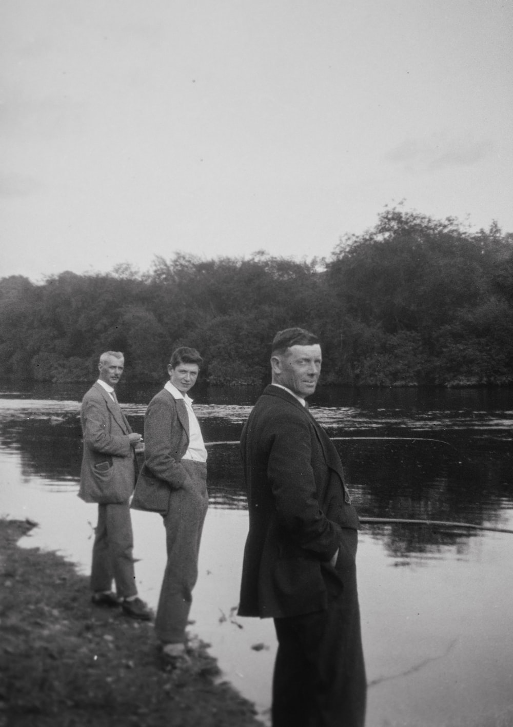 a group of men standing next to a river