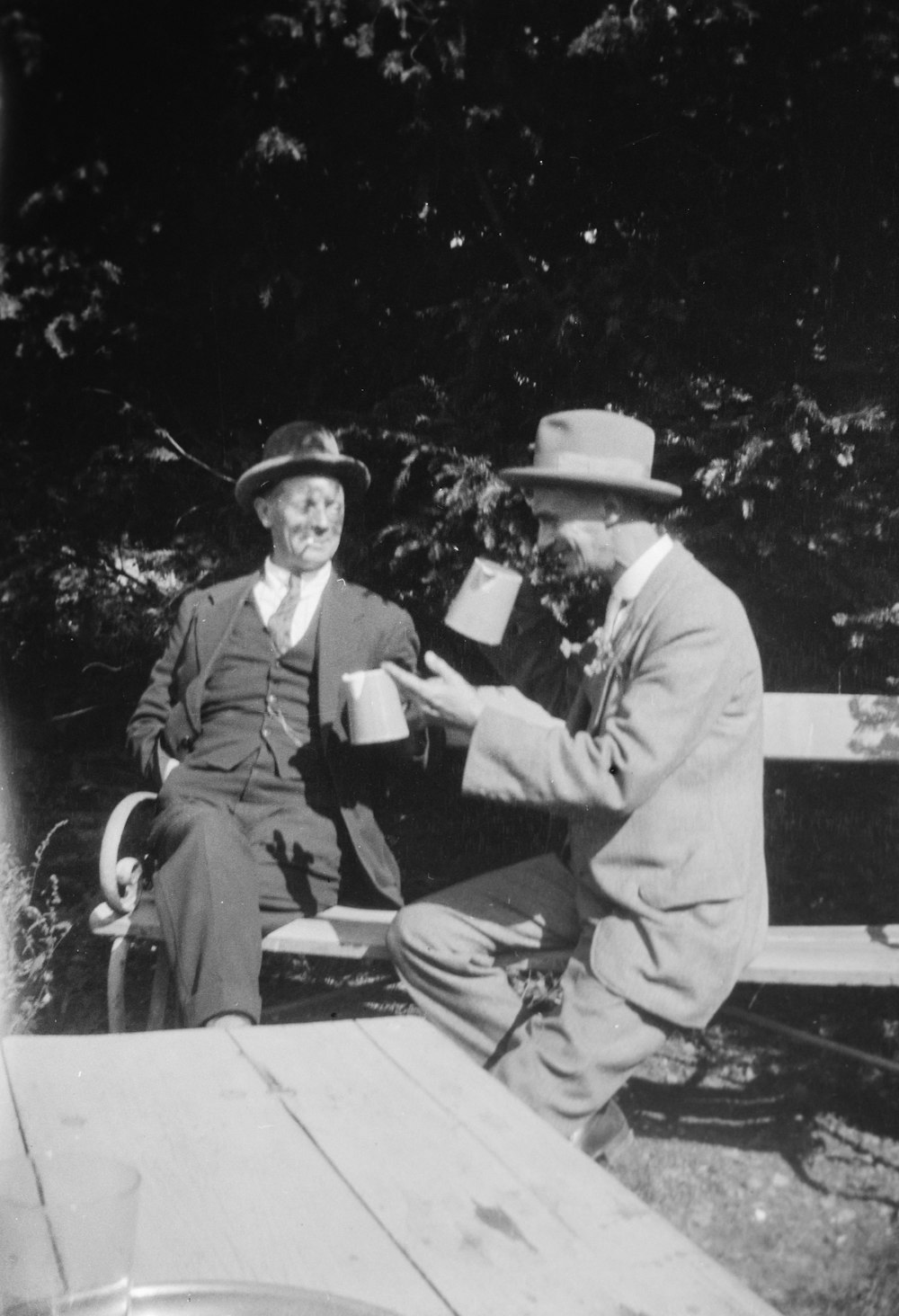 an old photo of two men sitting on a bench