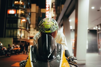 A biker wearing Moto Man gloves, gripping the handlebar with the Mumbai skyline in the background.