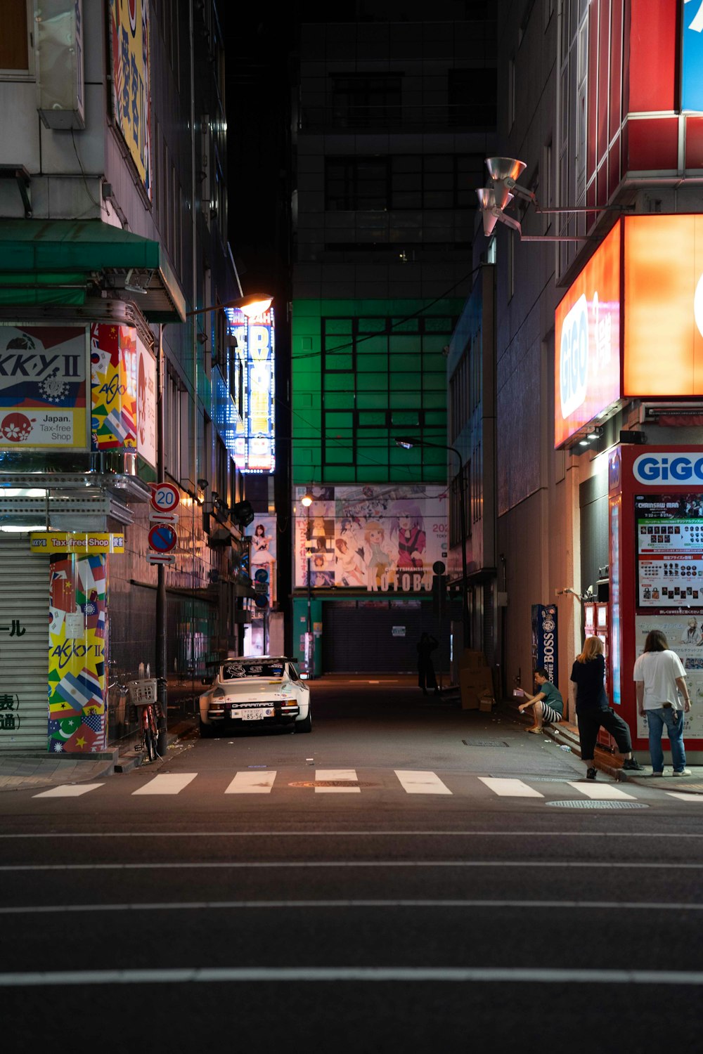 a city street at night with a car parked on the side of the road