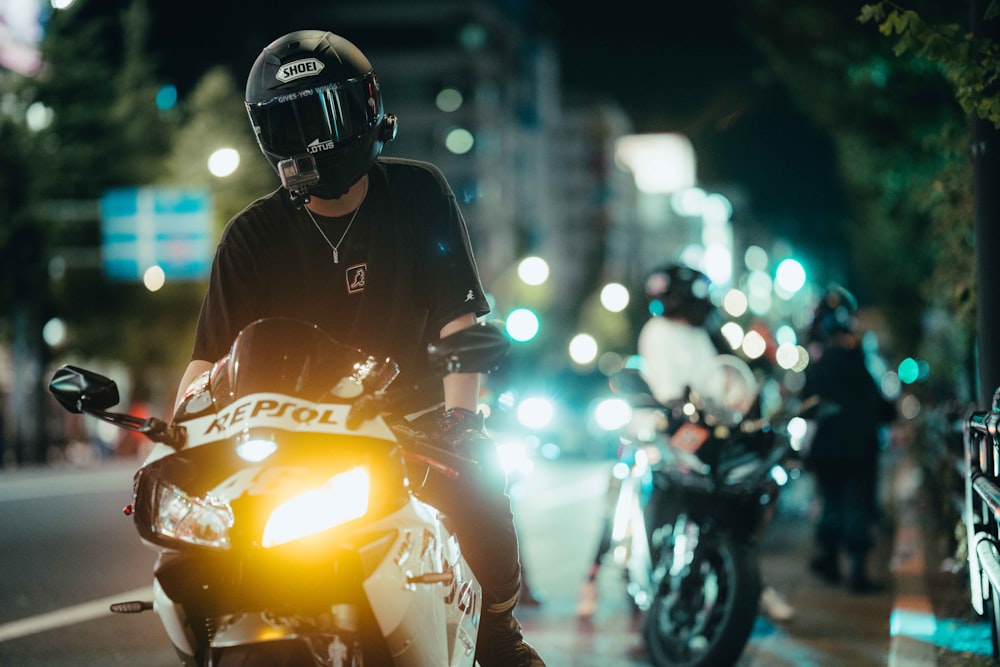 a man riding a motorcycle down a street at night