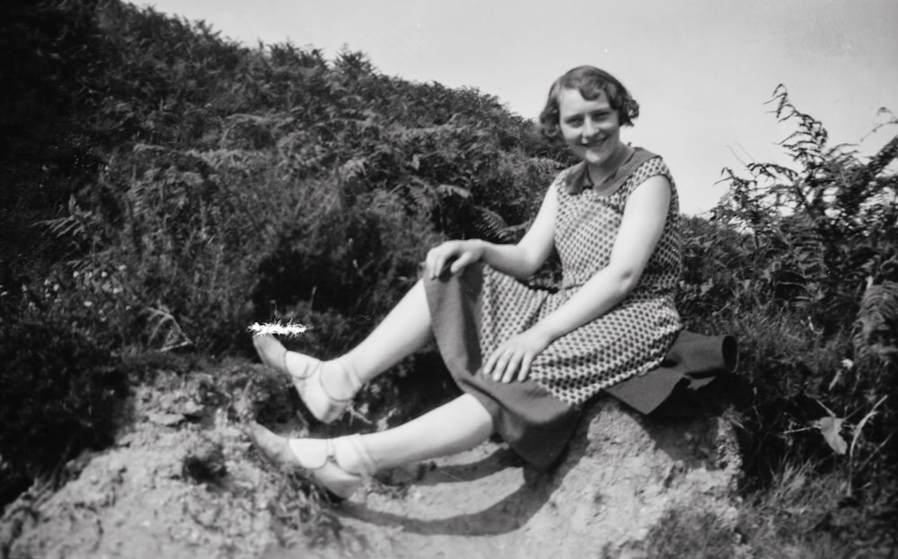 a woman sitting on a rock in a dress