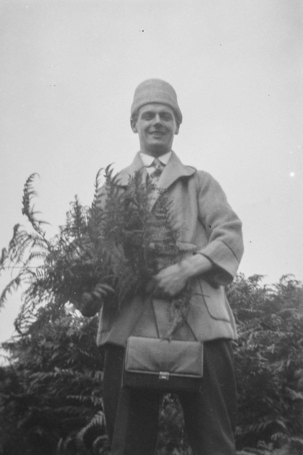 a black and white photo of a man holding a plant