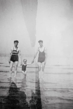 an old photo of a man and a woman holding a child's hand