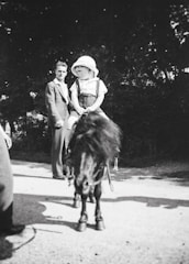 A cheerful child riding a gentle pony at a sunny county fair, with smiling families watching nearby.