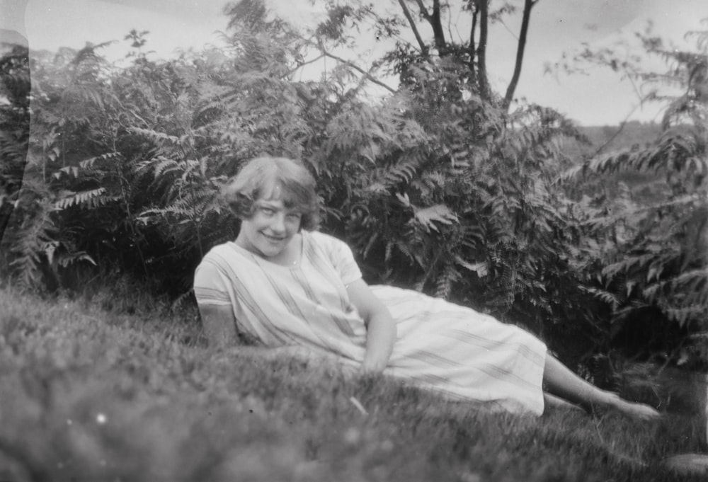 a woman in a white dress is laying in the grass