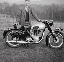 Murdered by Darkness Image  a man in a suit standing next to a motorcycle