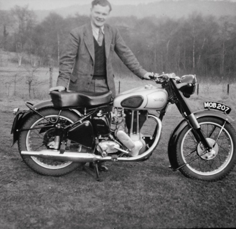 a man in a suit standing next to a motorcycle