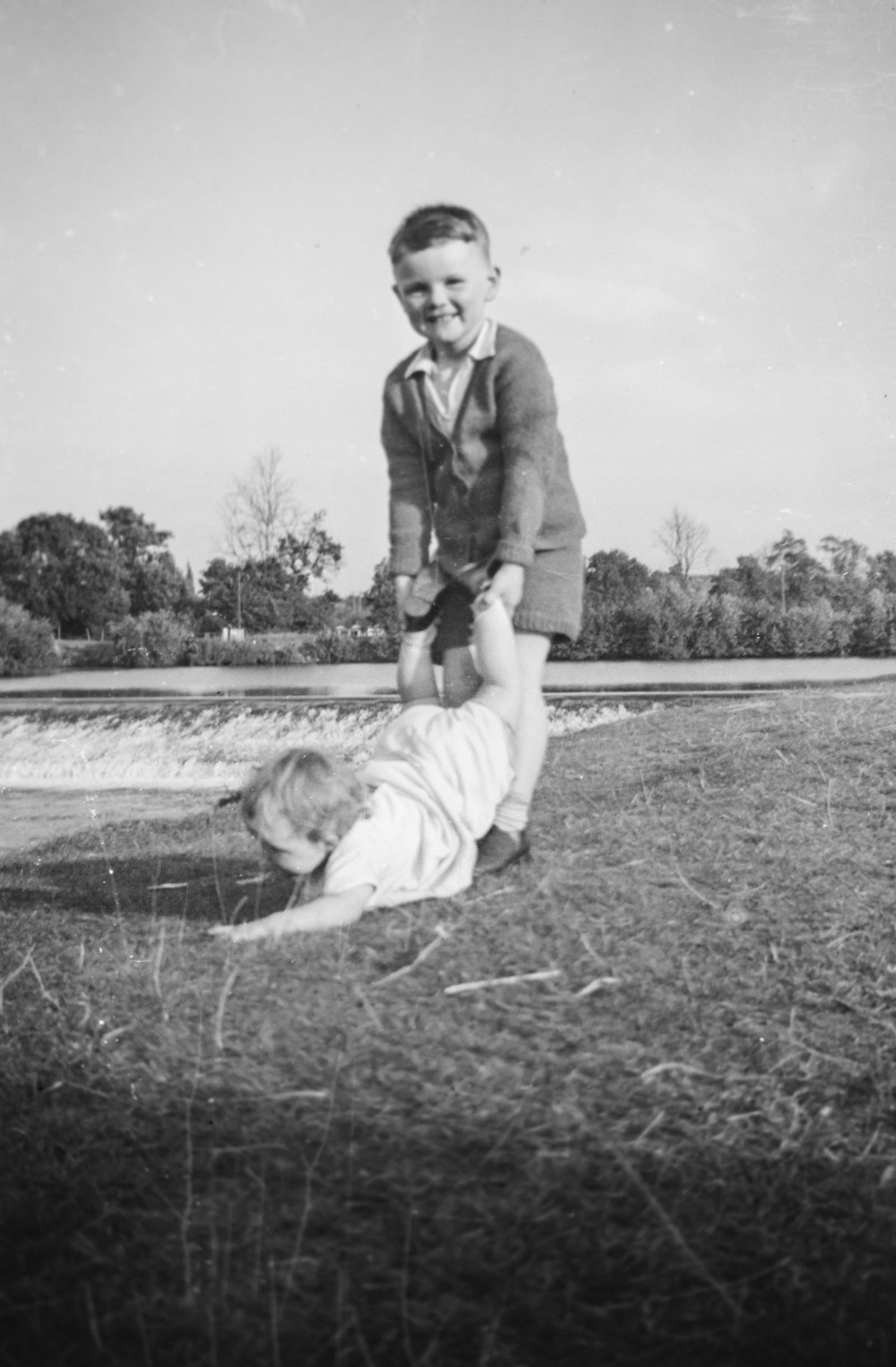 ein altes Foto eines kleinen Jungen, der mit einem Baby spielt