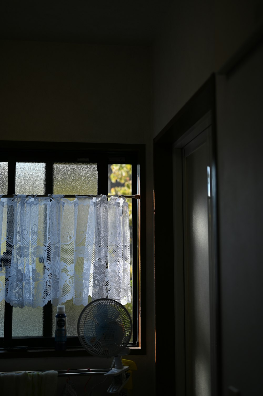 a fan sitting in front of a window next to a window curtain