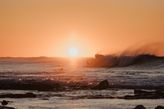 Surfer riding a powerful wave at sunset with golden light reflecting on the water.