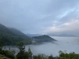 Mist rolling over a lush green valley with distant hills fading into the horizon.