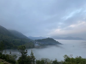 Mist rolling over a lush green valley with distant hills fading into the horizon.