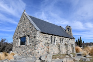 a stone church with a steeple on a rocky hillside