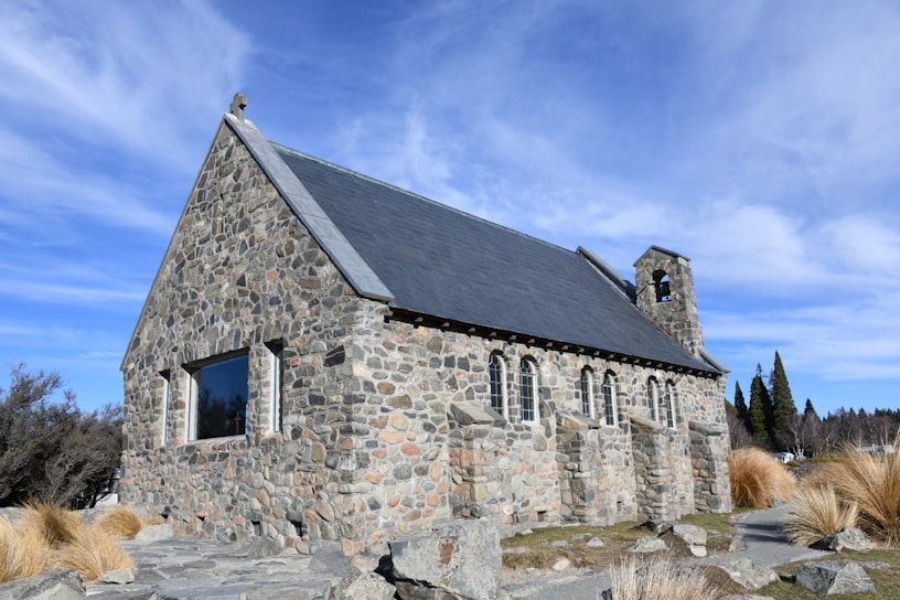 a stone church with a steeple on a rocky hillside