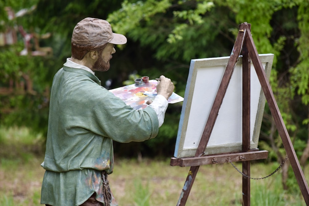 a statue of a man holding a paintbrush and painting a picture