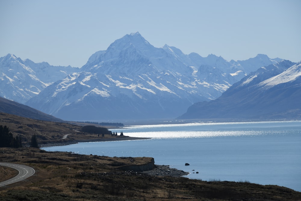 uma vista panorâmica de uma cordilheira com um lago em primeiro plano