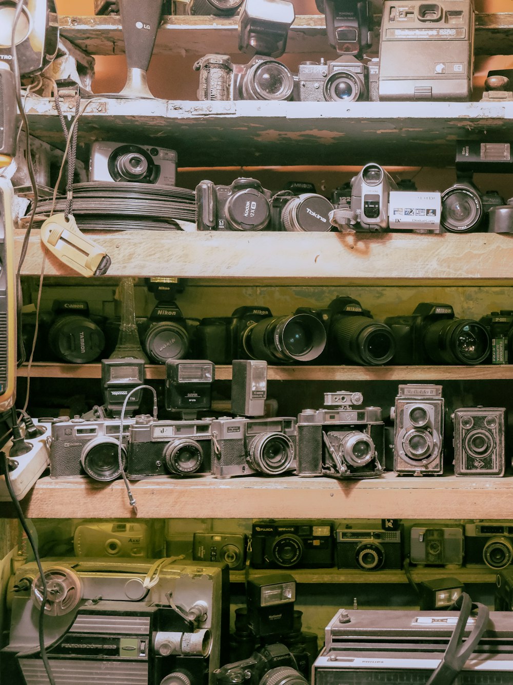 a bunch of cameras are stacked on a shelf