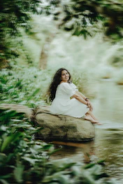 A serene woman sitting peacefully in nature, reflecting calm and healing.