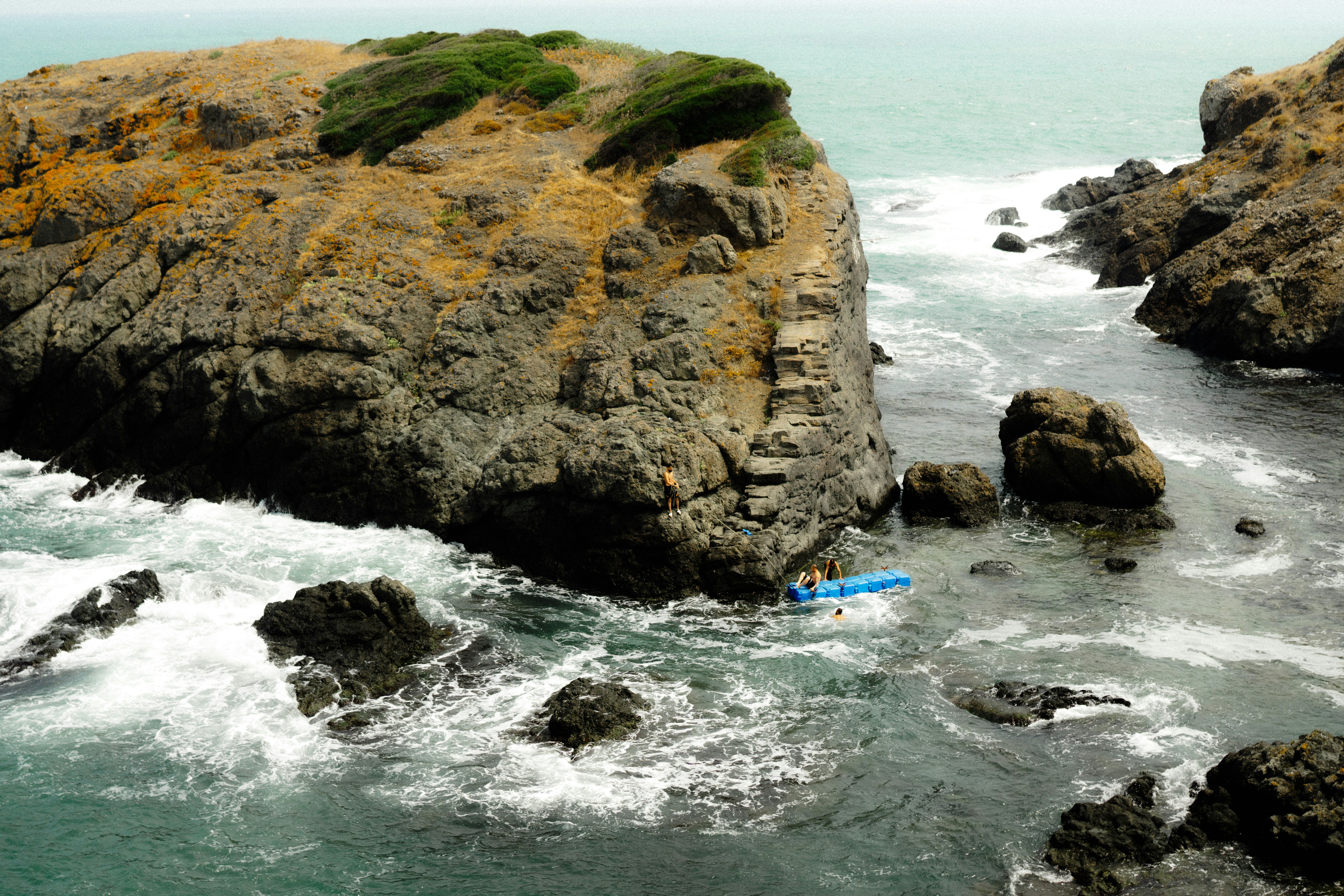 a blue surfboard is in the water near some rocks