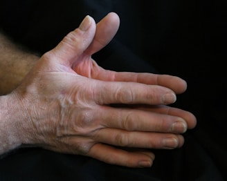Close-up of hands expressing emotion, set against a soft gray background with pink accents.
