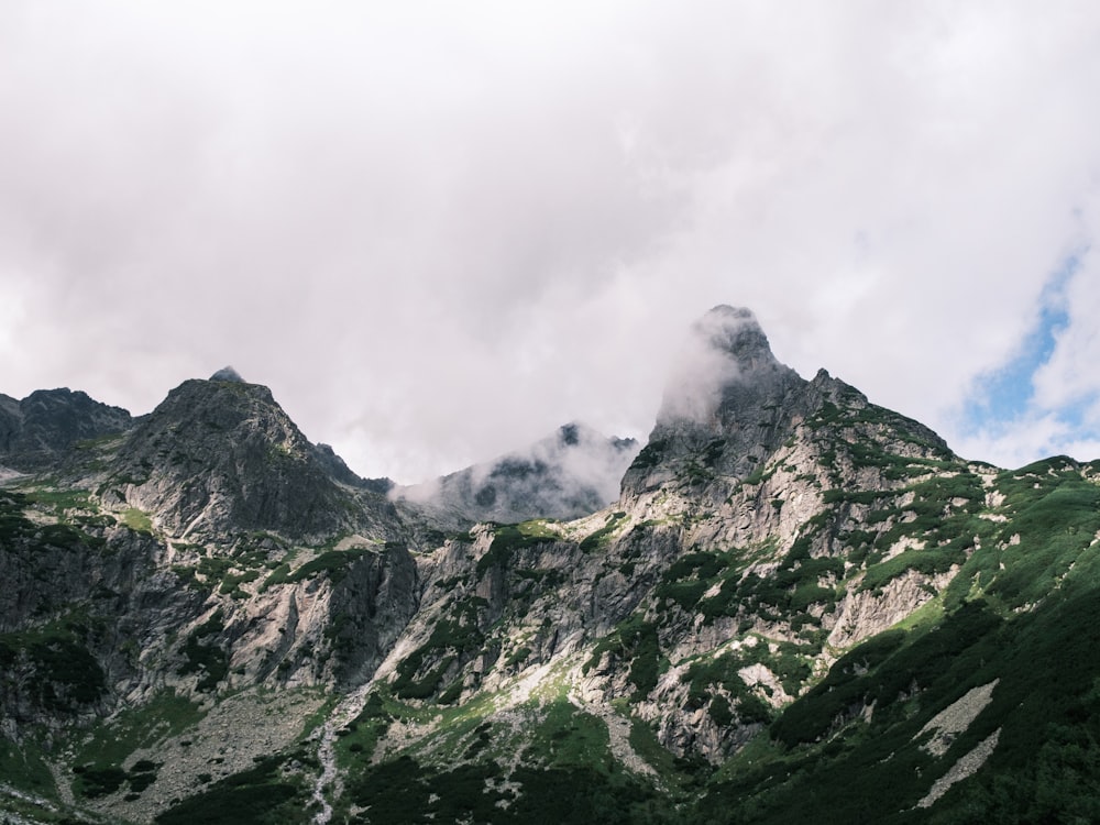 a mountain range covered in green grass and clouds