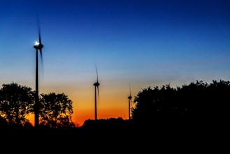 A vibrant wind farm at sunset with turbines turning gently against a colorful sky.