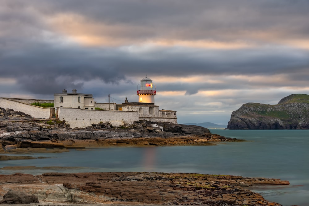 a lighthouse on a rocky shore under a cloudy sky