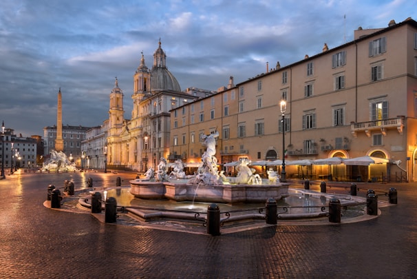 A quiet, empty piazza bathed in soft blue and gold light, evoking metaphysical architecture with long shadows.