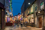 Historic cobblestone streets lined with charming cafes under warm evening lights.