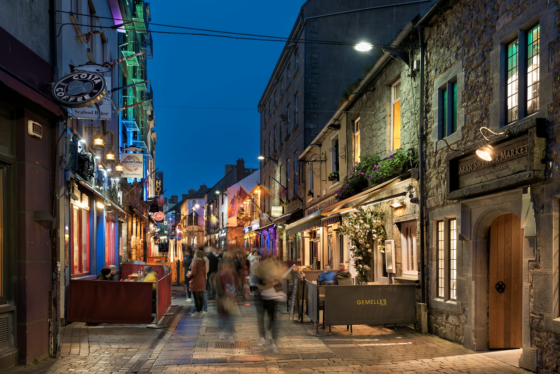 A charming cobblestone street lined with quaint shops and twinkling fairy lights in the evening.