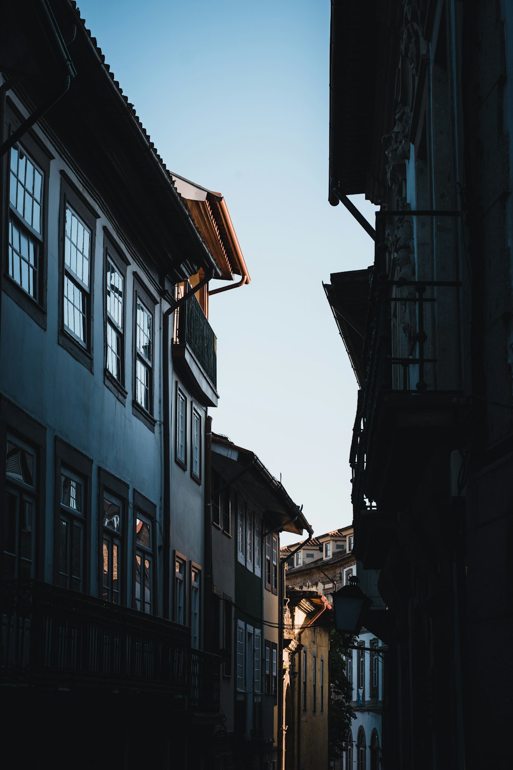 a narrow alley way with buildings and a clock tower in the distance