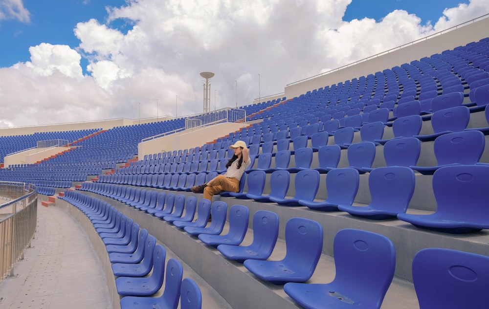a person sitting on a blue chair in a stadium