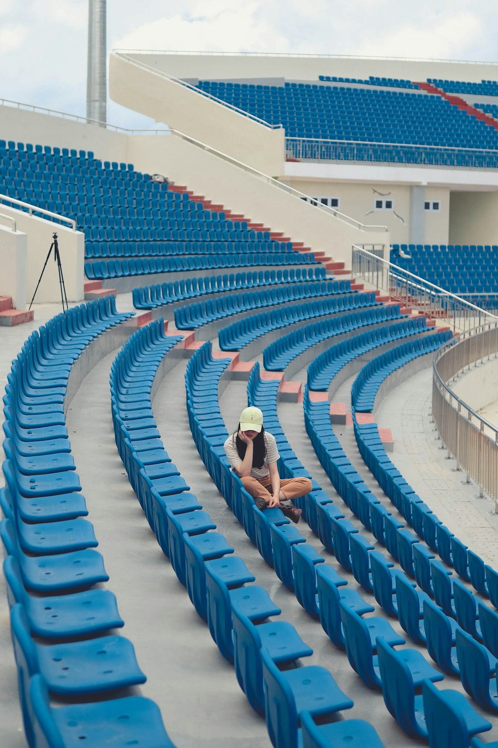 a woman sitting on a blue stadium bleachers