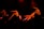Several dancers in motion, captured under low red lighting. They are dressed in light tops and dark bottoms, performing expressive movements with their arms extended. The environment is dark, creating dramatic shadows and highlighting their dynamic poses.