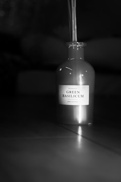 Artistic shot of a hydrosol bottle with steam rising, surrounded by fresh herbs on a dark surface.