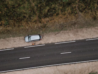 A friendly technician helping a stranded driver beside a broken-down car on a quiet road