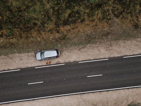 A friendly technician helping a stranded driver beside a broken-down car on a quiet road