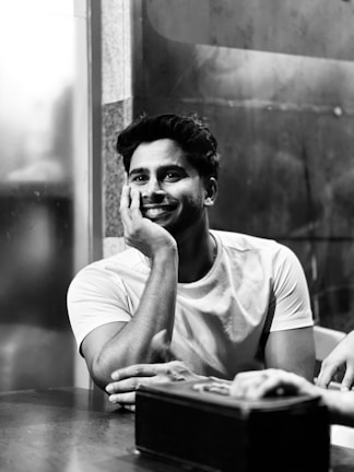 A black and white photo of a person smiling while recording a video for the weekly story series.