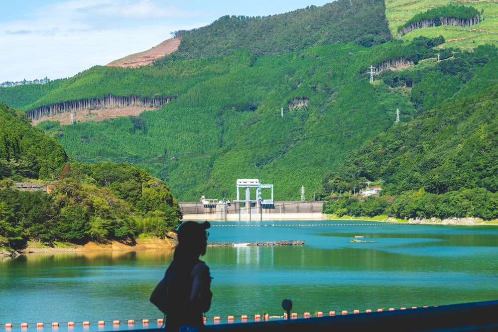 a person standing on the side of a road near a body of water